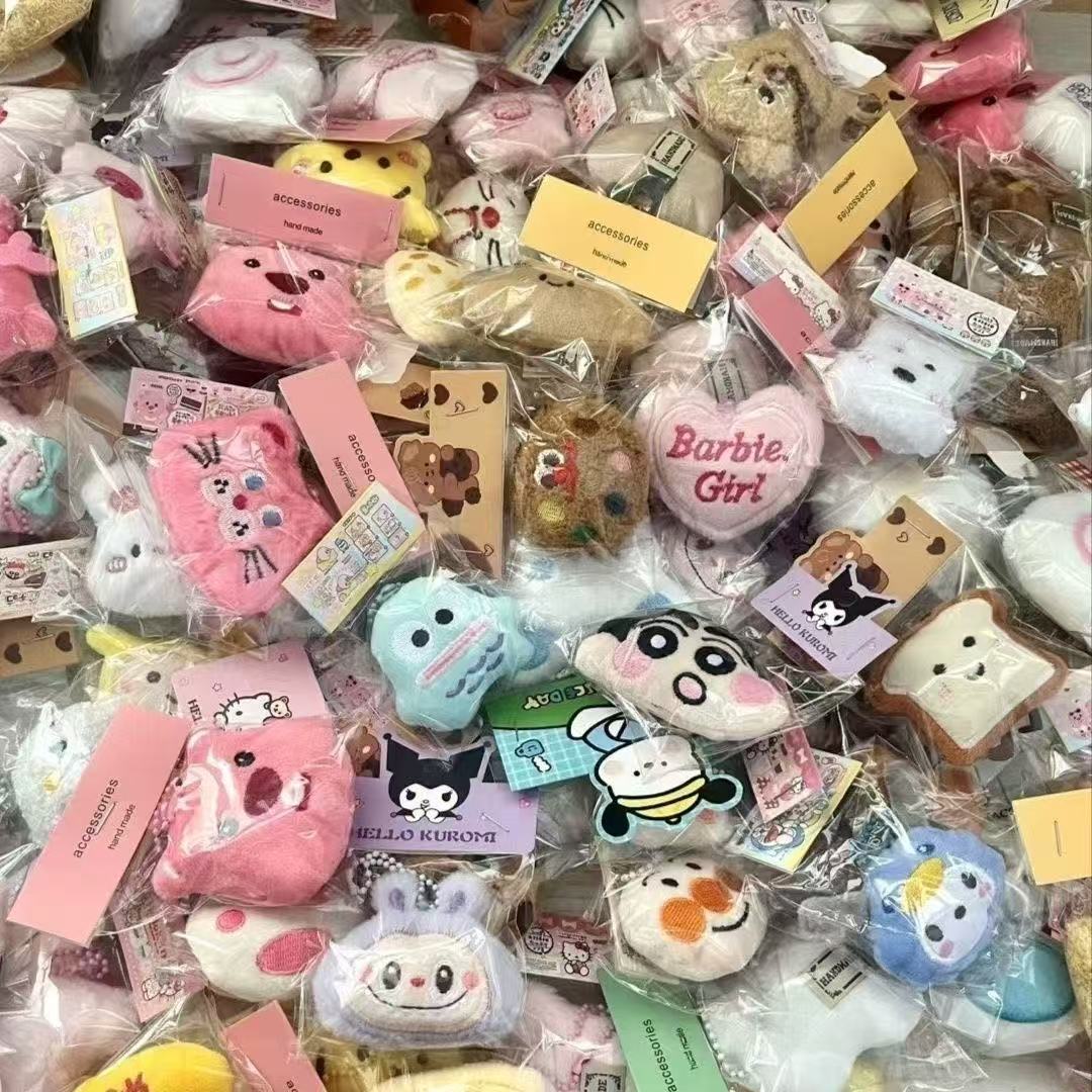 Colorful collection of plush doll keychains displayed in packaging, featuring various adorable designs and cartoon characters.
